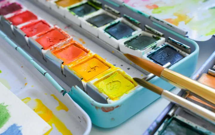 A tin of watercolour paints with two brushes